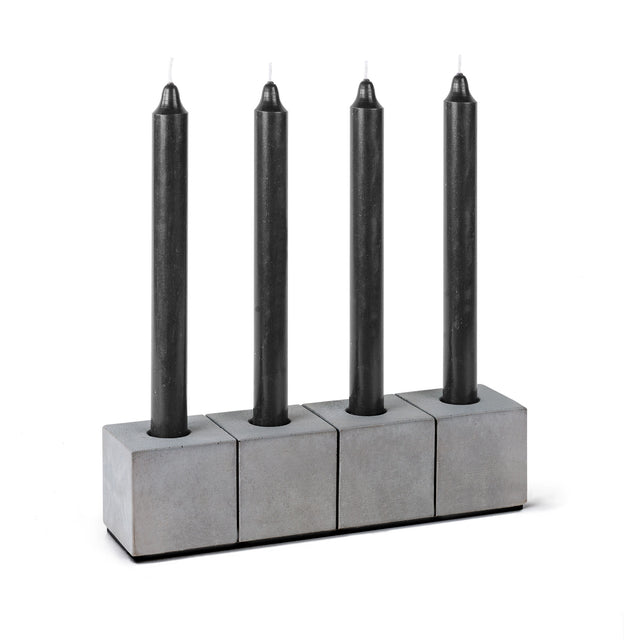 Kerzenhalter aus Beton mit vier schwarzen Stabkerzen, optisch wirkt es wie vier einzelne Kerzenhalter