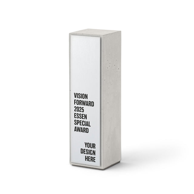 Betontrophäe mit aufgesetzter Aluminiumplatte und schwarzem Schriftzug „Vision Forward 2025 Essen Special Award“.