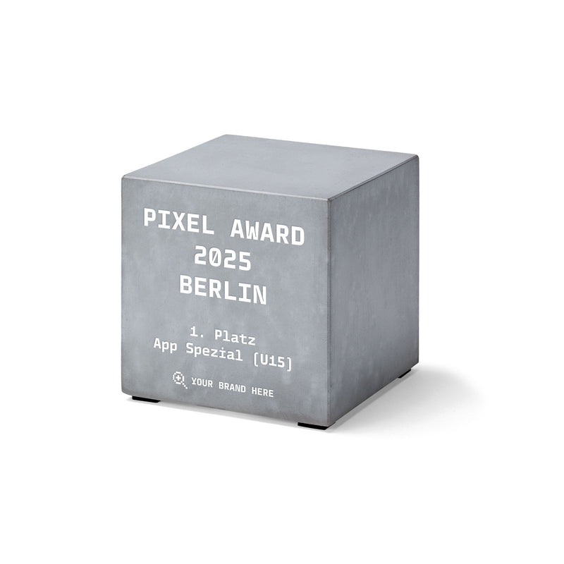Kubischer Award aus grauem Beton mit Aufdruck „Pixel Award 2025 Berlin – 1. Platz App Spezial (U15)“.