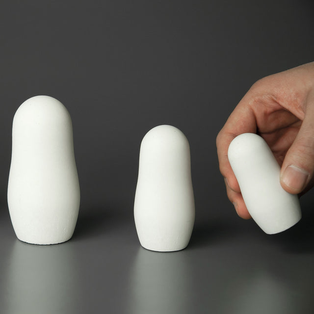 Eine Hand hält eine weiße Matrjoschka aus weißem Beton