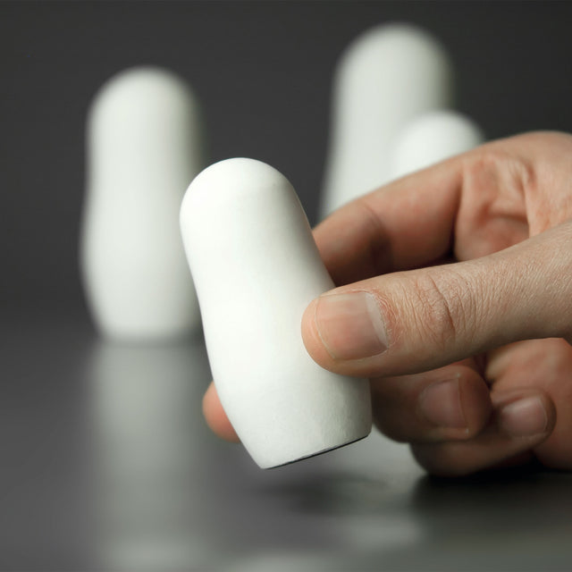 Eine Hand hält eine schlichte weiße Matrjoschka aus weißem Beton