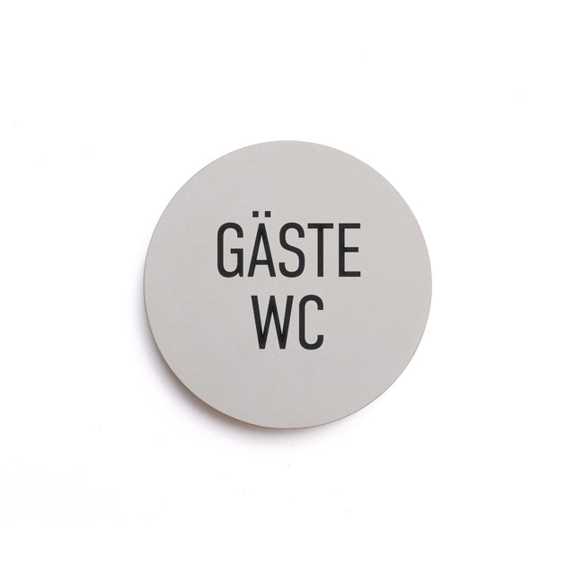 Hinweisschild aus Beton mit dem Text: GÄSTE WC