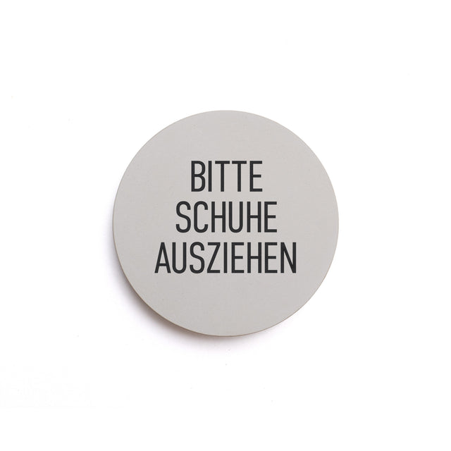 Hinweisschild aus Beton mit dem Text: BITTE SCHUHE AUSZIEHEN