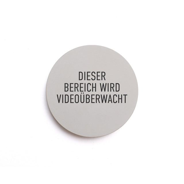 Hinweisschild aus Beton mit dem Text: DIESER BEREICH WIRD VIDEOÜBERWACHT