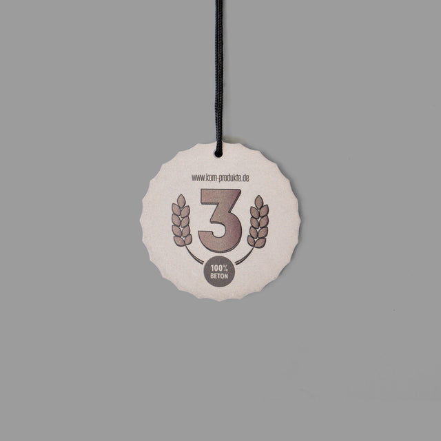 Minimalistisch gestaltete Betonmedaille mit auffälligen Kanten, UV-Druck und eleganter schwarzer Kordel.